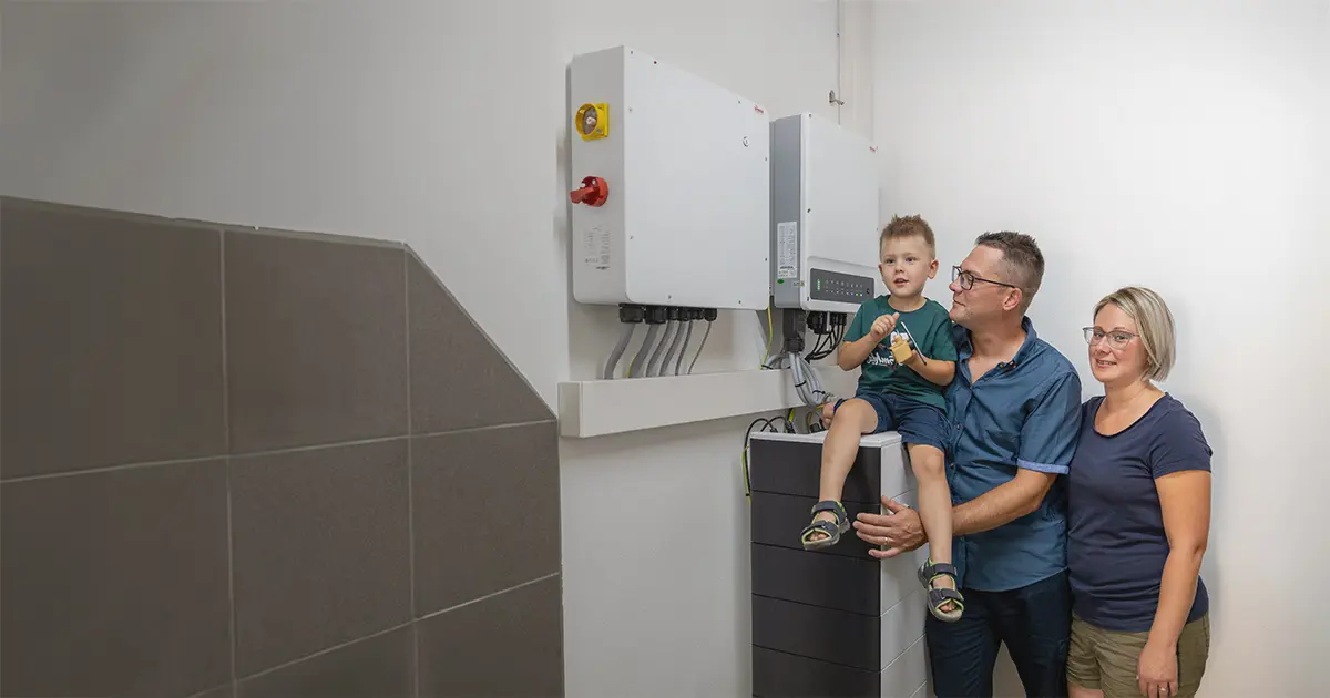 Eine Familie die vor einem neu gekauften Stromspeicher steht.