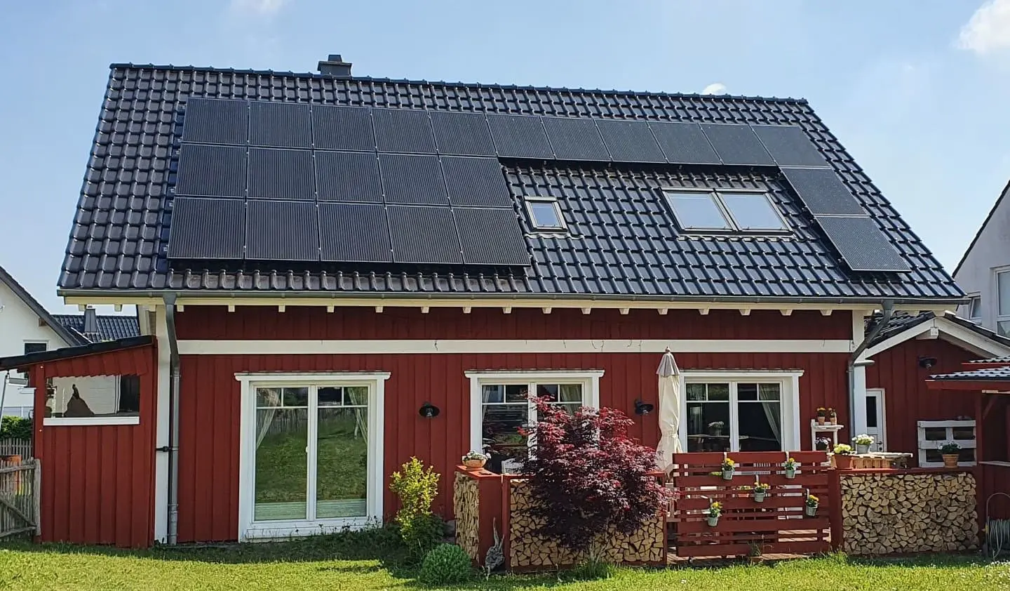 Ein rotes Haus mit Photovoltaikanlage auf dem Dach.