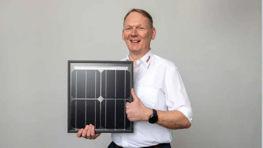Der Geschäftsinhaber von enerix Westküste hält ein kleines Photovoltaikmodul in der Hand.
