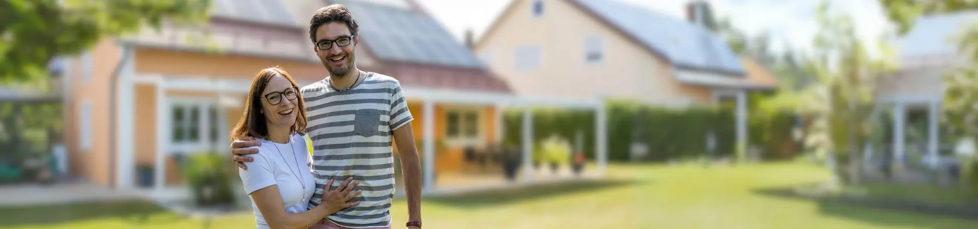 Ein Ehepaar steht im Garten vor ihrem Haus mit einer Photovoltaikanlage.