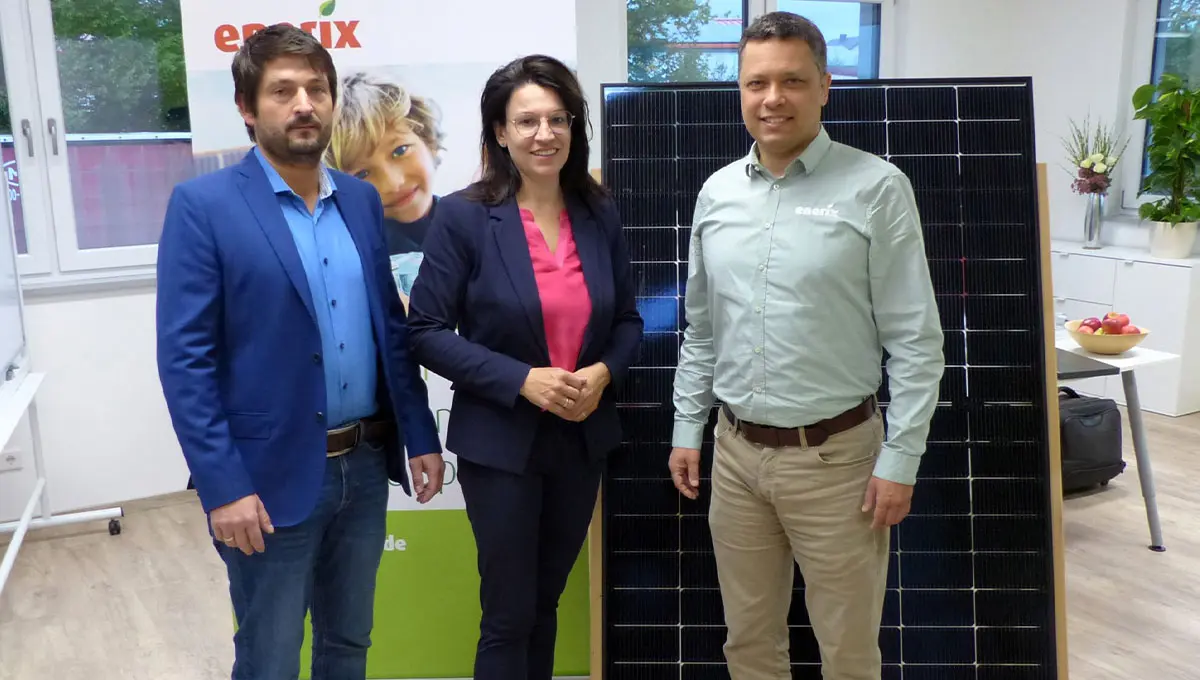 mdB Martina Engelhardt, Gerhard Wegmann von enerix Cham und Bürgermeister Martin Bauer stehen im Büro von enerix Cham vor einem Photovoltaikmodul.