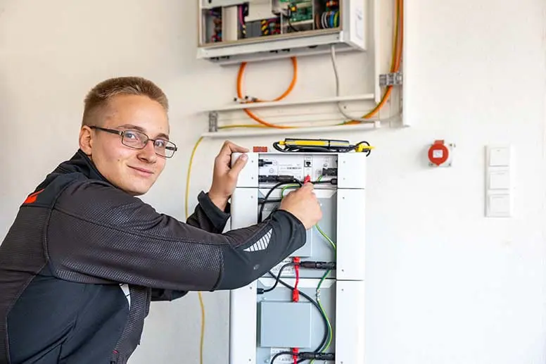 Ein Elektroniker von enerix aus Feucht bei Nürnberg arbeitet an einem Stromspeicher