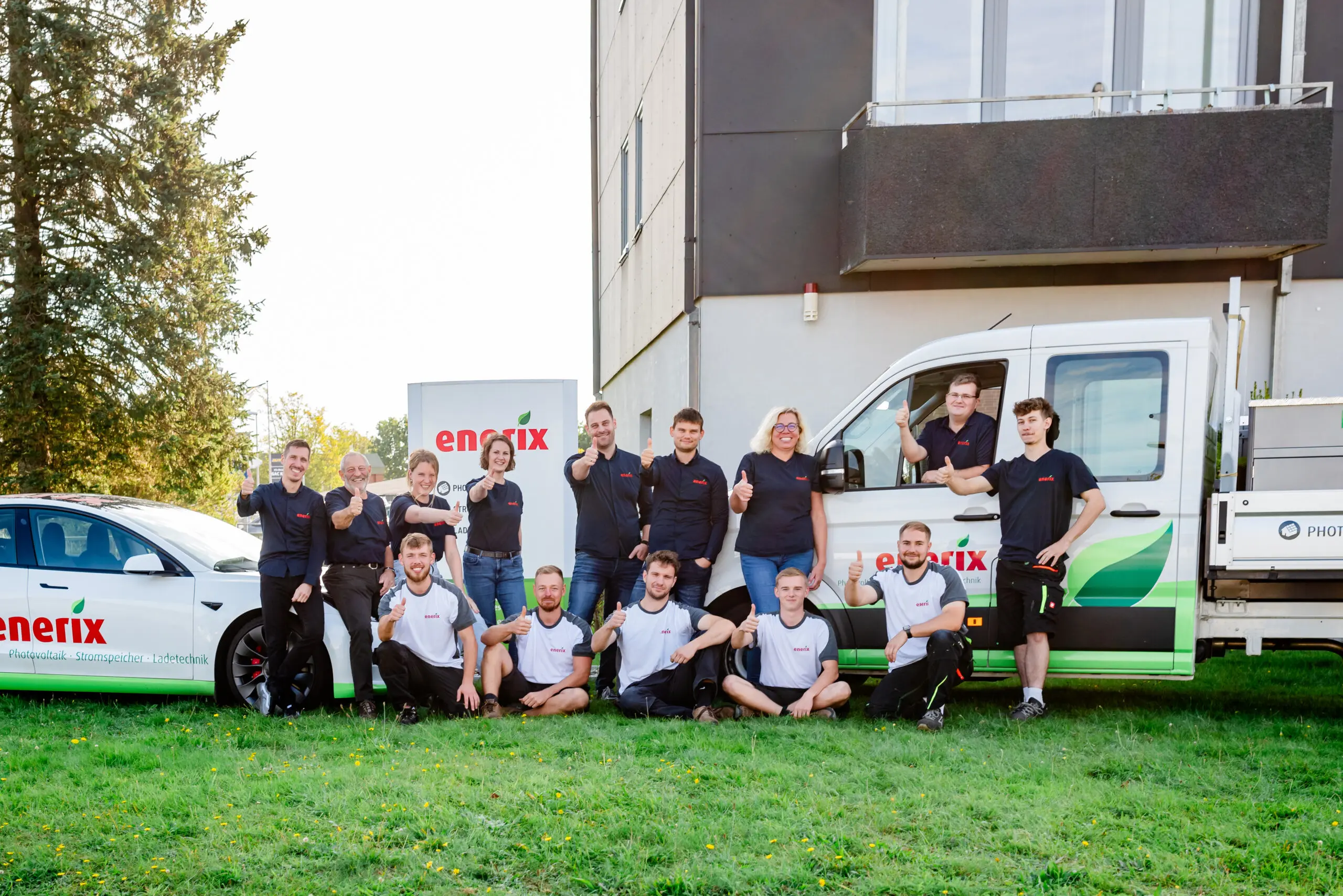 Das Team von enerix Nord-Ostsee steht vor 2 enerix Fahrzeugen.