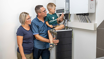 Familie steht vor einem Stromspeicher