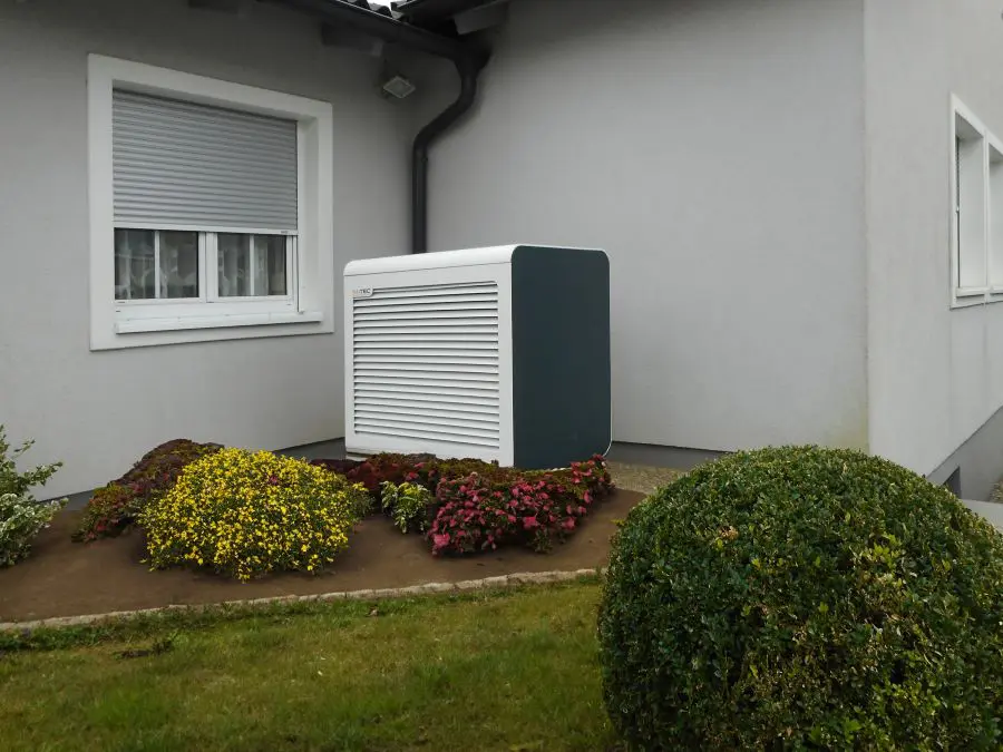Eine Luft Waermepumpe vor einem Einfamilienhaus.