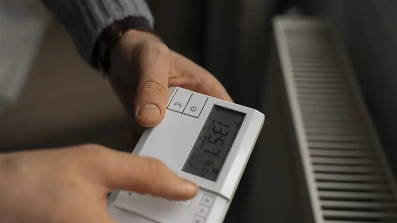 Person stellt Heizkörper über Thermostat ein