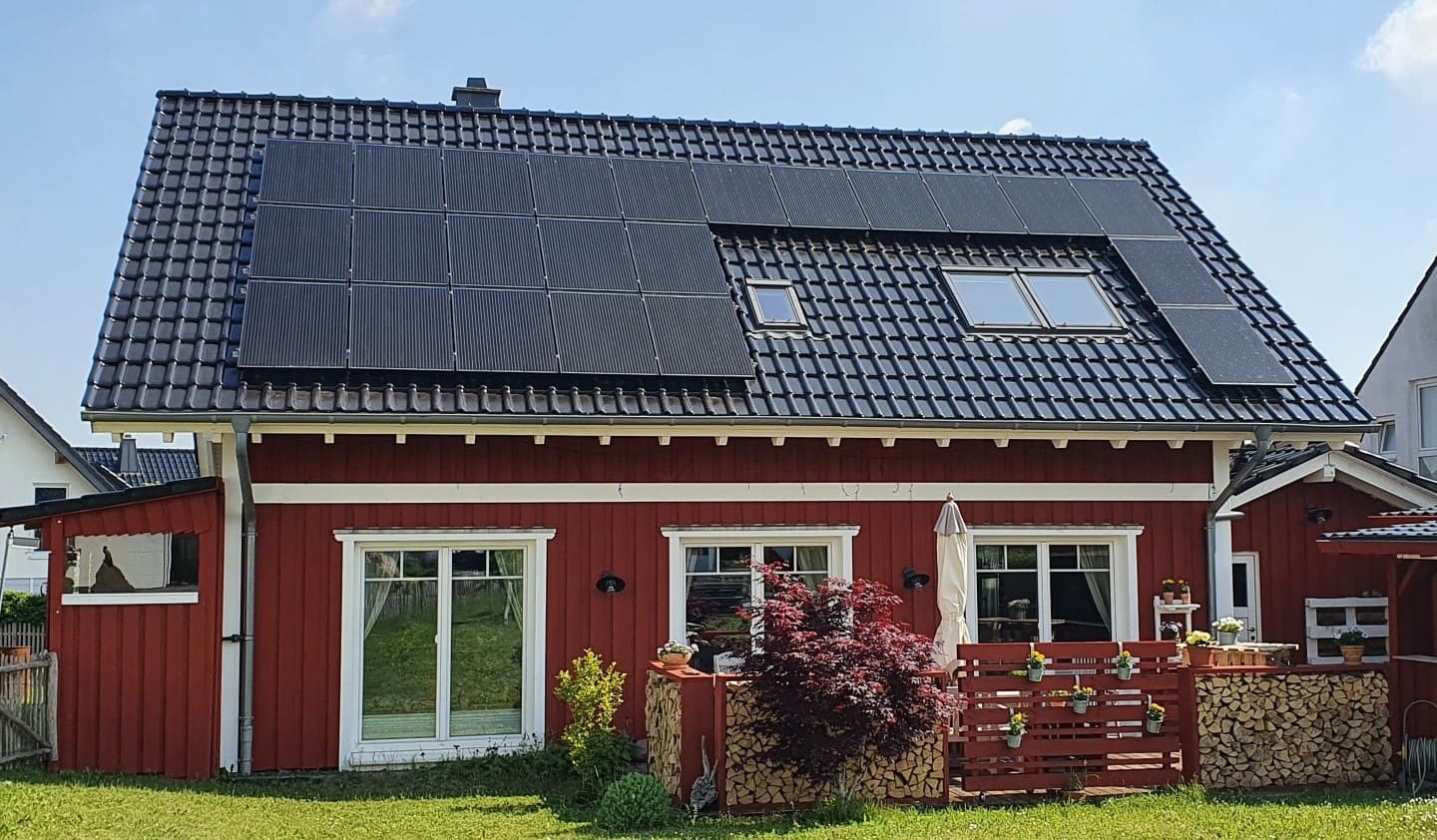 Ein rotes Haus mit Photovoltaikanlage auf dem Dach.