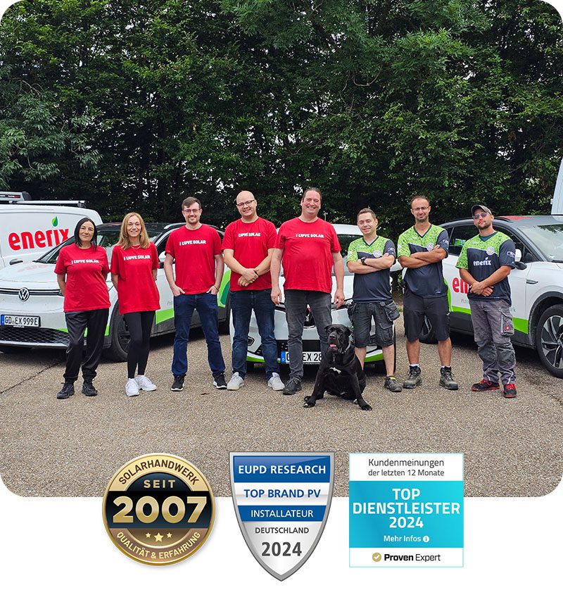 Ein Team von Enerix-Mitarbeitern aus der Region Ostalb-Schwäbisch Hall posiert vor mehreren Firmenfahrzeugen. Die Mitarbeiter tragen rote T-Shirts mit der Aufschrift „I LOVE SOLAR“ oder Enerix-Arbeitskleidung. Ein schwarzer Hund sitzt vor der Gruppe. Im Vordergrund sind drei Auszeichnungen zu sehen: „Solarhandwerk seit 2007“, „Top Brand PV Installateur Deutschland 2024“ und „Top Dienstleister 2024“.