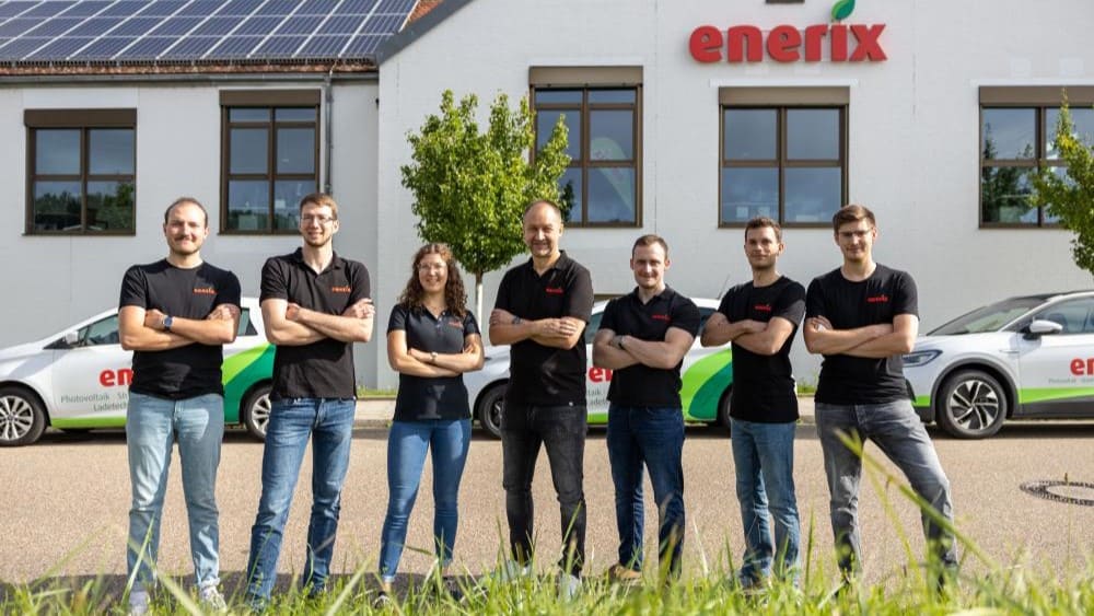 Das Vertriebsteam von enerix Regensburg steht vor drei enerix PKWs und dem Büro von enerix Regensburg.