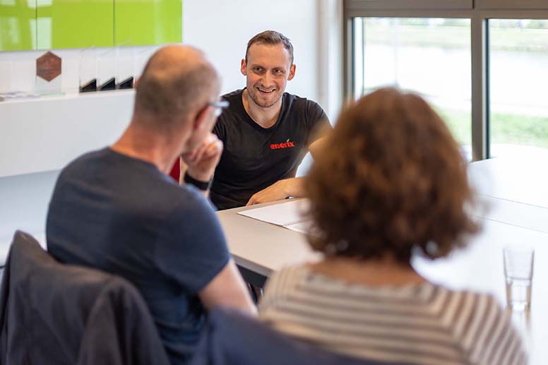 Ein Photovoltaik Spezialist berät ein Ehepaar an einem Tisch