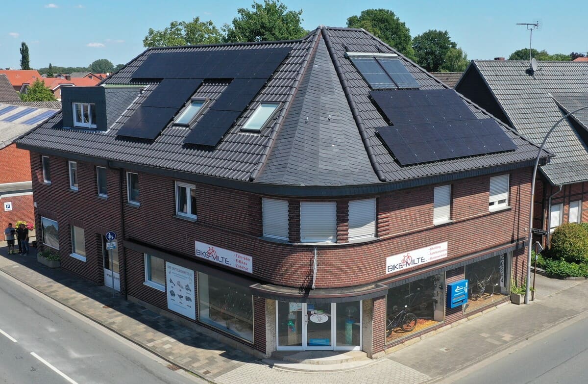 Ein Mehrfamilienhaus aus Backsteinziegeln und einer Photovoltaikanlage auf dem Dach.