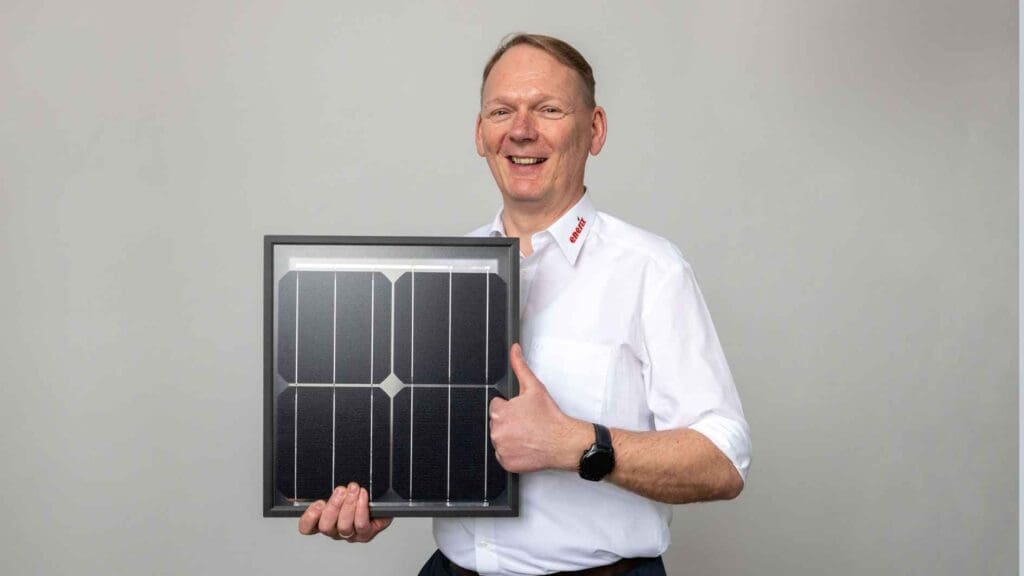 Der Geschäftsinhaber von enerix Westküste hält ein kleines Photovoltaikmodul in der Hand.