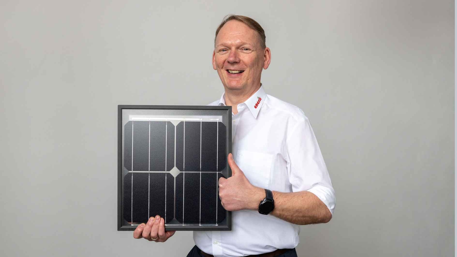 Der Geschäftsinhaber von enerix Westküste hält ein kleines Photovoltaikmodul in der Hand.