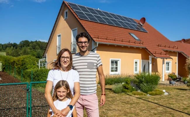 Eine junge Familie steht vor ihrem Haus mit einer neu montierten Photovoltaikanlage von enerix.