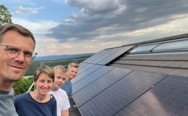 Eine Familie aus dem Schwarzwald steht vor ihrer neuen Photovoltaikanlage und freut sich über das fertige Ergebnis.