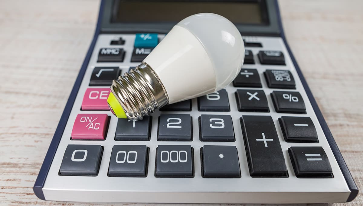 Ein Stromkostenrechner und auf der eine Glühbirne liegt