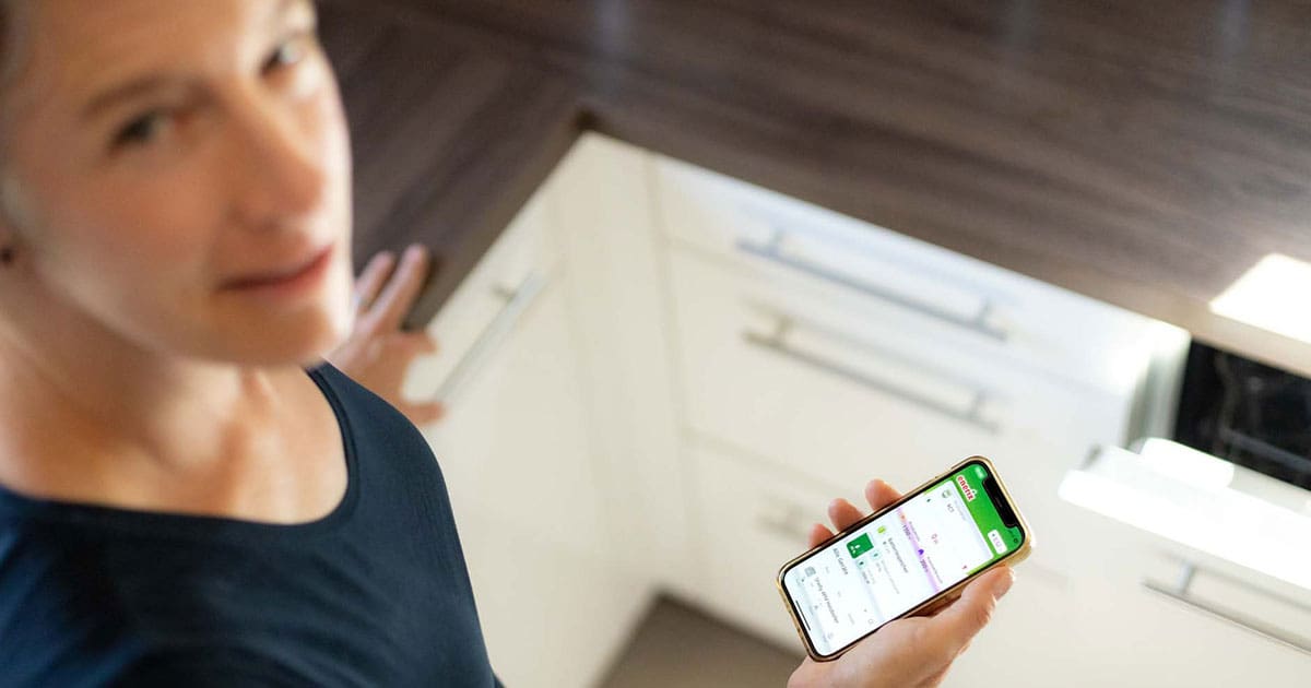 Eine Frau hält ein Handy in der Hand mit enerixControl geöffnet.
