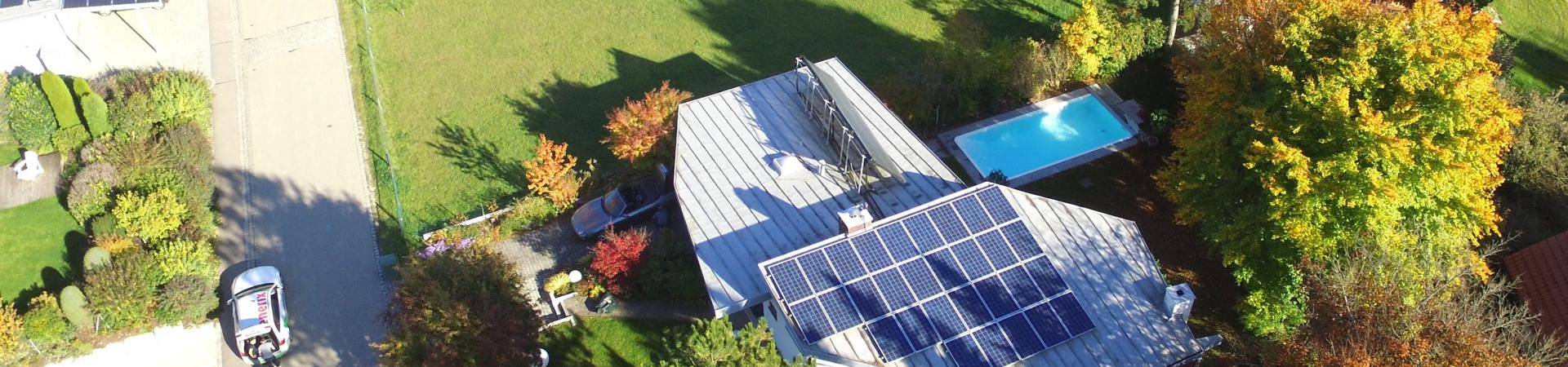 Ein modernes Einfamilienhaus mit einer Photovoltaikanlage auf dem Dach und einem Pool im Garten.