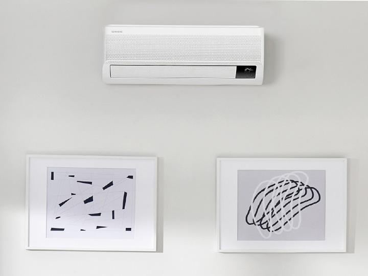 Ein kompaktes Samsung Windfree Klimagerät hängt an einer Wild über zwei Bildern