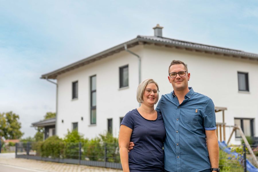 Eine glückliche Familie vor einem Einfamilienhaus. 