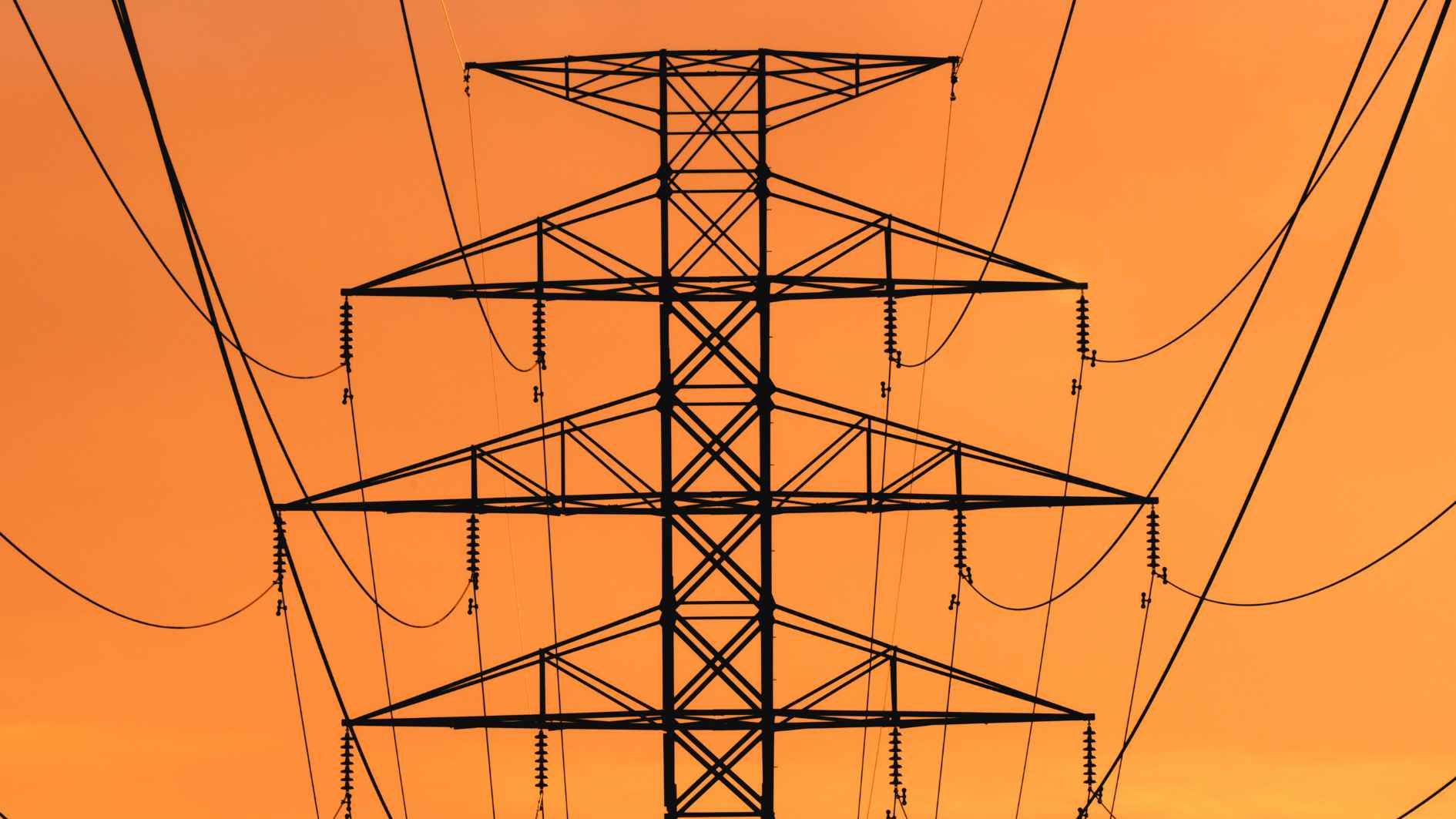 Ein Strommast von einer Hochspannungsleitung bei Abenddämmerung.