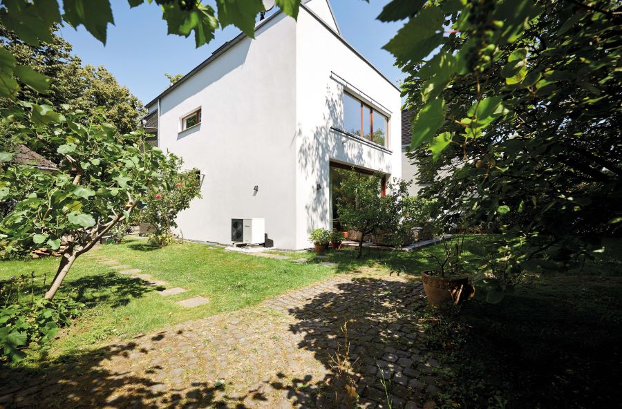 Eine Wärmepumpe steht im Frühling vor einem Einfamilienhaus.