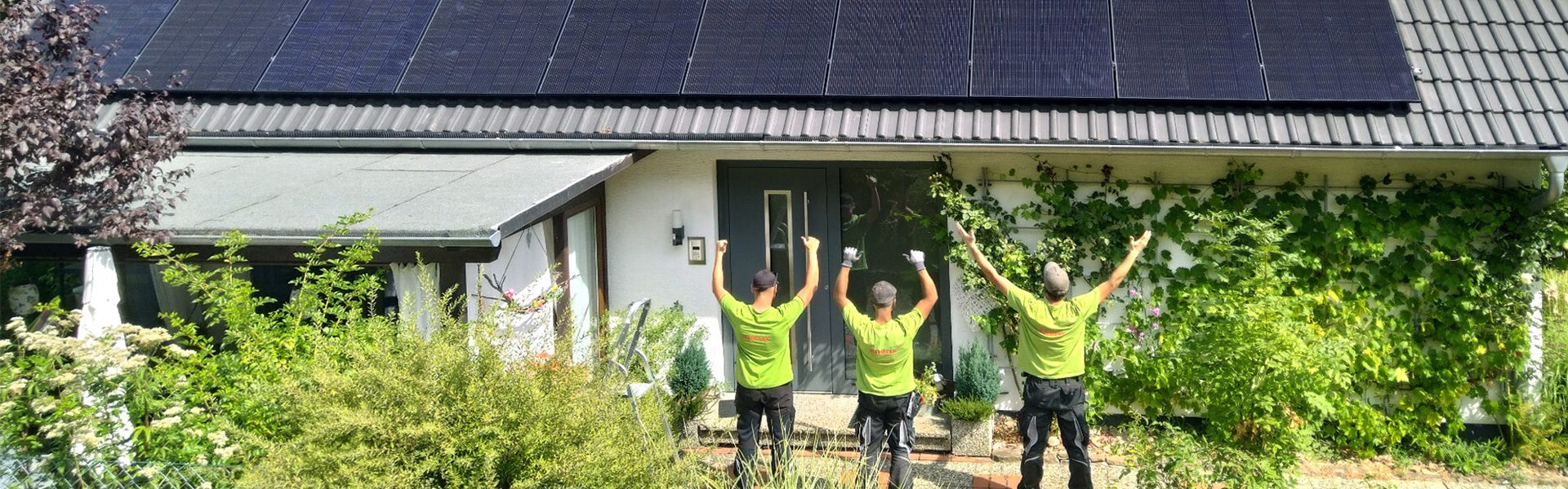 Ein Team von Photovoltaik Montagepartnern von enerix steht vor einem Haus und freut sich über eine fertig montierte Solaranlage