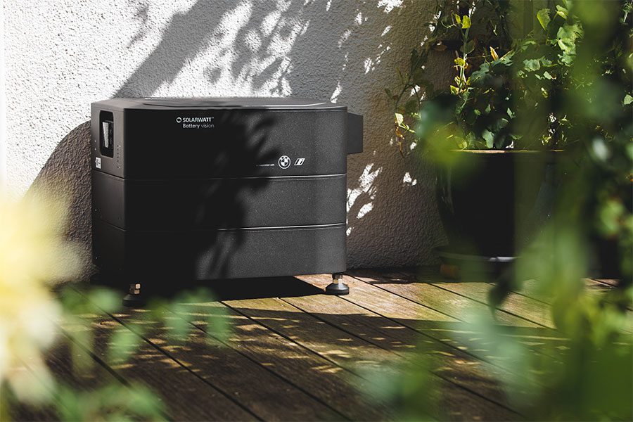 Ein Solarwatt Stromspeicher der vor einer Hauswand steht
