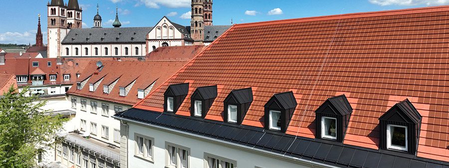 Dach mit roten Solardachziegeln auf dem Gebäude der Kongregation der Schwestern des Erlösers in Würzburg; die PV-Anlage ist kaum von den umliegenden klassischen Ziegeln zu unterscheiden.