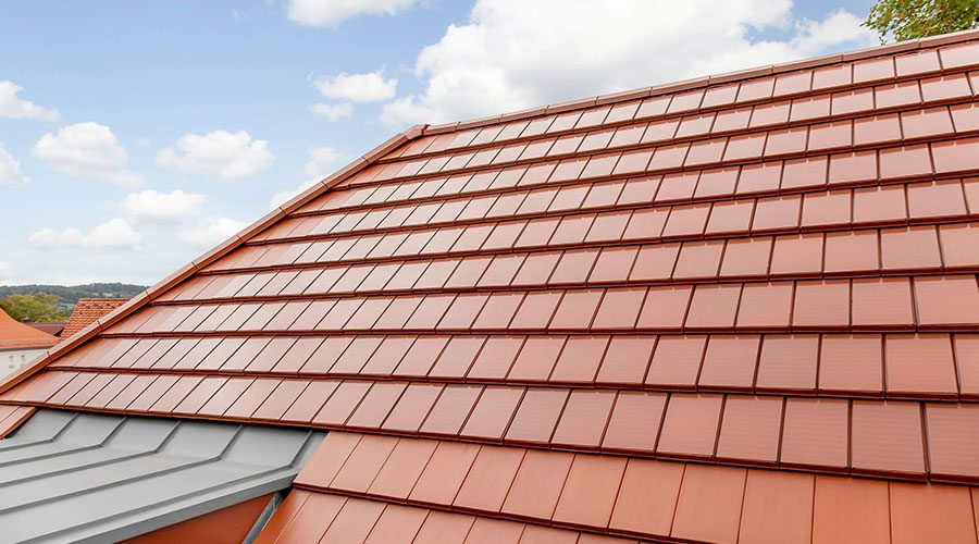 Ein Hausdach mit roten Solardachziegeln bedeckt.