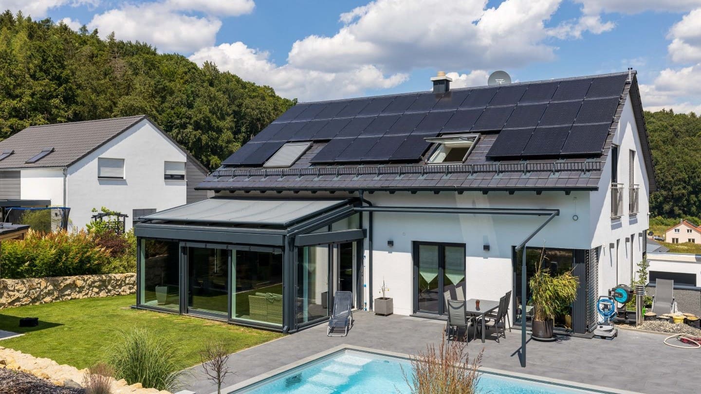 Ein Haus mit einer Solaranlage auf dem Dach und einem Pool im Vordergrund. Das Haus steht im Landkreis Regen