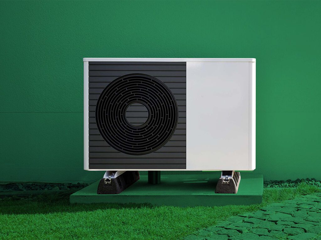 Eine Wärmepumpe steht vor einer Hauswand.