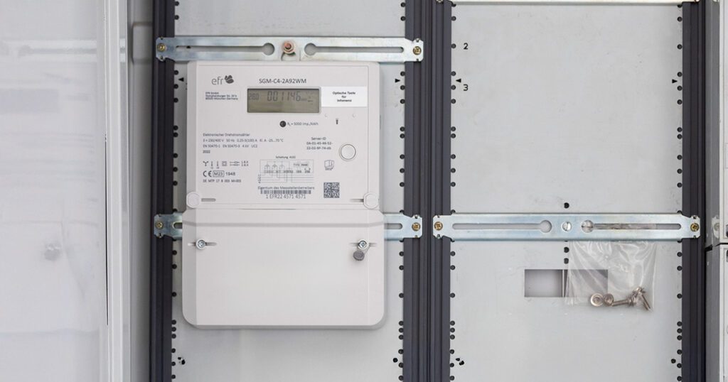 Moderner elektronischer Drehstromzähler in einem Zählerschrank montiert.
