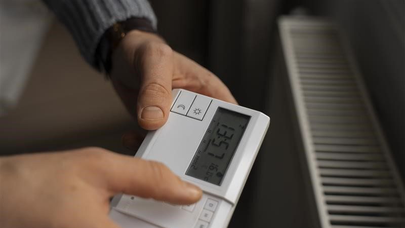 Person stellt Heizkörper über Thermostat ein