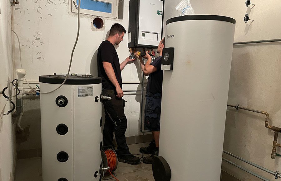 Enerix Monteure installieren eine Wärmepumpe in einem Keller