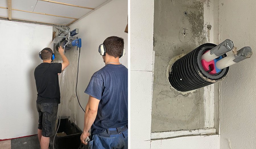 Zwei Handwerker bohren ein Lock für mit einem Kernlochbohrer in eine Kellerwand für die Wärmepumpenzuleitung