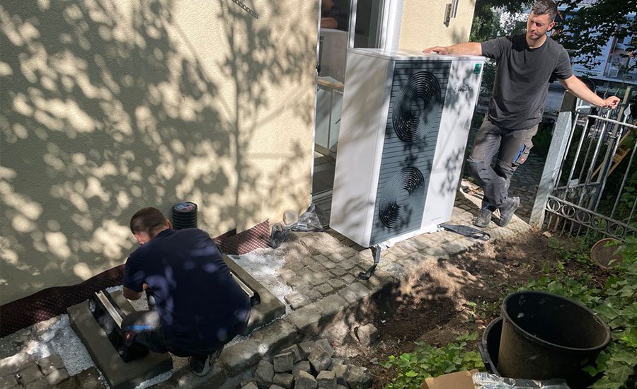 Zwei Handwerker installieren das Außengerät einer Vaillant Wärmepumpe