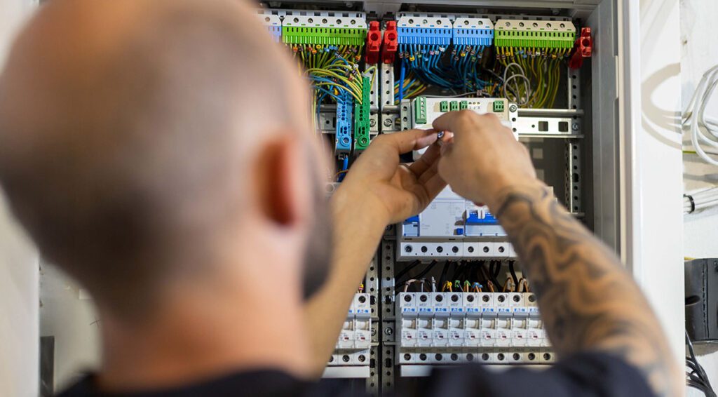 Ein Mann arbeitet an den elektrischen Kabeln eines Sicherungskastens