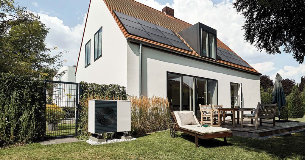 Modernes Einfamilienhaus mit Photovoltaikanlage auf dem Dach und Wärmepumpe im Garten – die ideale Kombination für niedrige Heizkosten